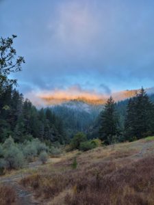 Sunlight lights up a ridge line above a river canyon 